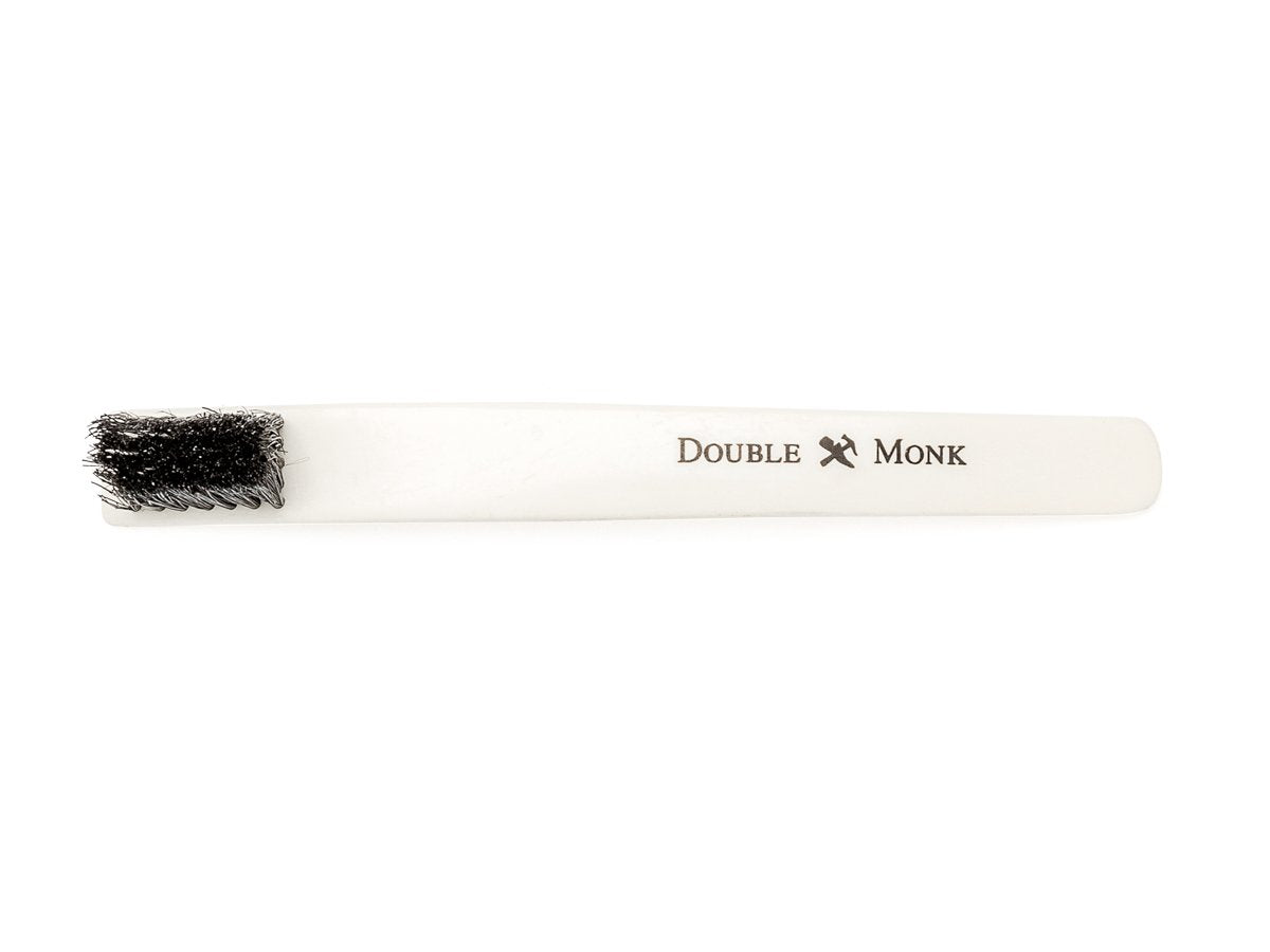 Top view of toothbrush sized bone shoe polishing brush with black bristles showing Double Monk logo