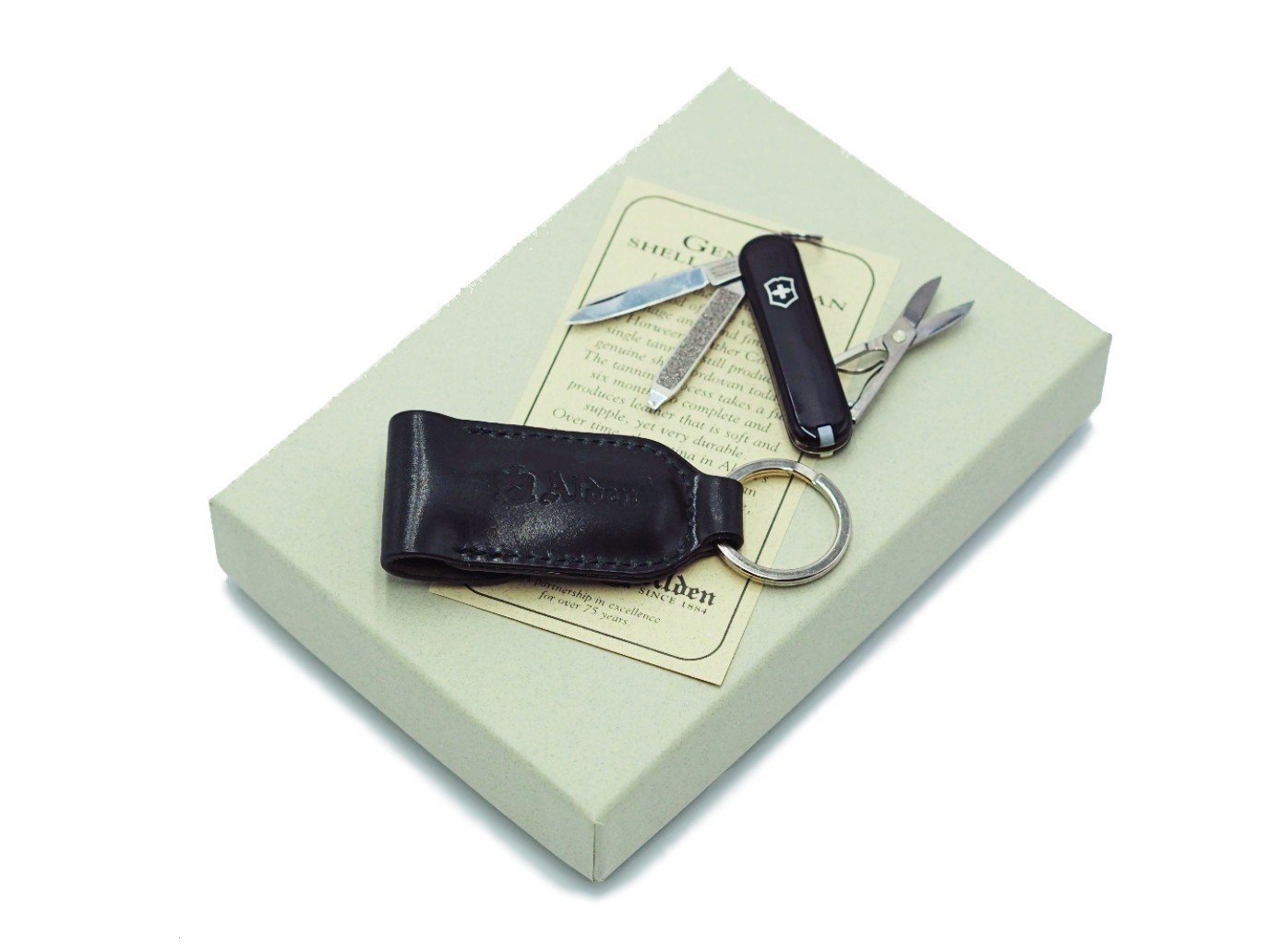 Swiss army knife and Alden black shell cordovan knife case with key ring on top of box