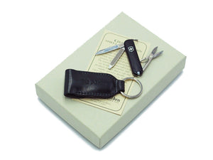 Swiss army knife and Alden black shell cordovan knife case with key ring on top of box