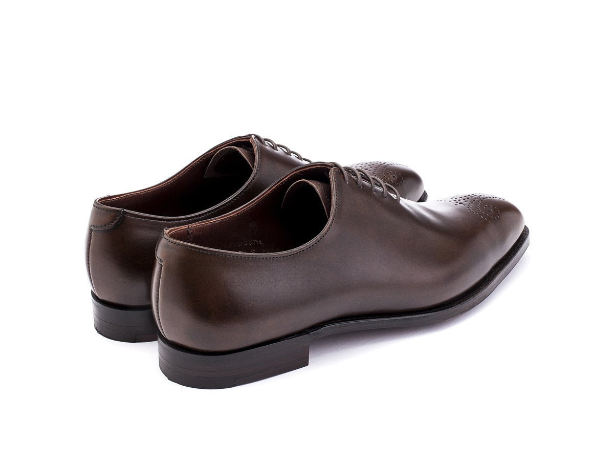 Back angle view of Crockett & Jones Weymouth wholecut medallion oxford shoes in dark brown antique calf