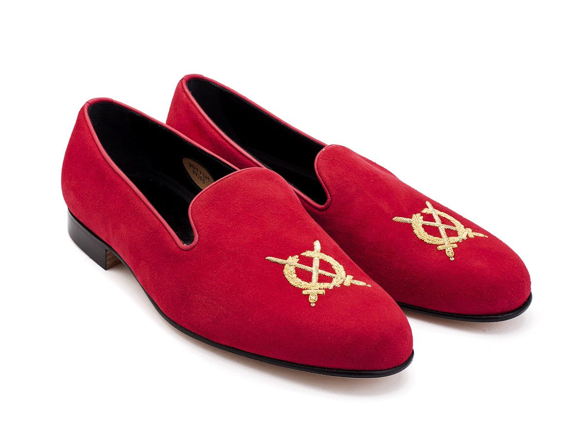 Front angle view of F width Edward Green Royal Albert slippers in scarlet suede with hand embroidered gold wreath and swords crest on toe