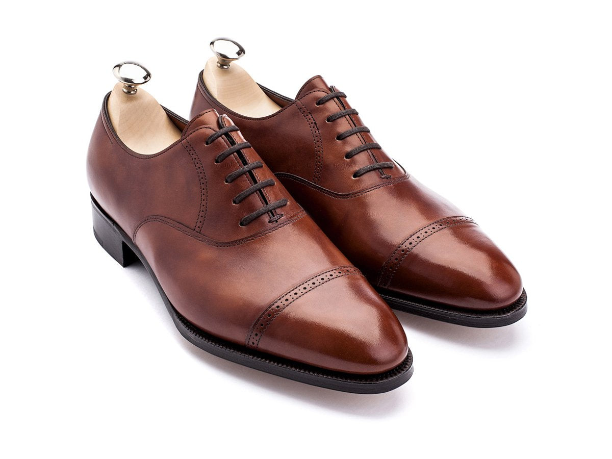 Front angle view of John Lobb Philip II quarter brogue oxford shoes in chestnut misty calf with shoe trees